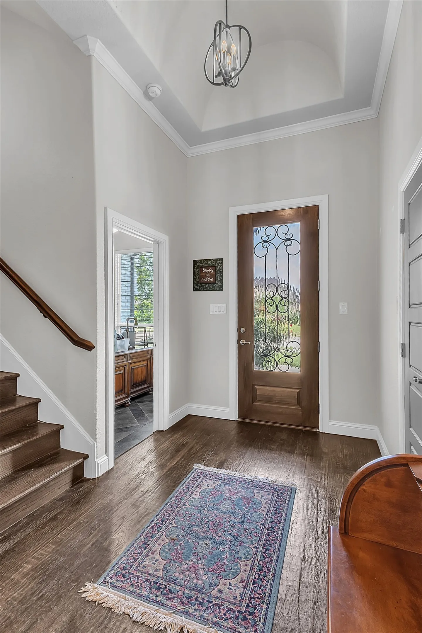Entryway featuring wood-finish flooring, a decorative glass front door, and a coffered ceiling with a contemporary light fixture
