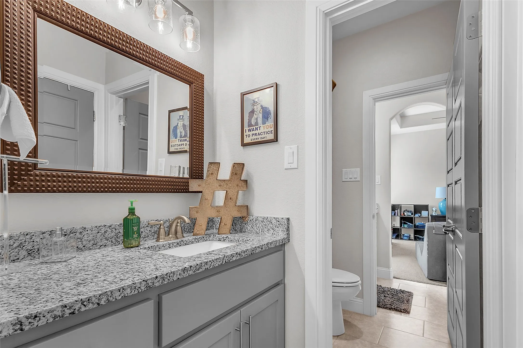 Jack & Jill Bathroom featuring a linen closet, glass-enclosed shower, granite countertop, framed mirror, brushed nickel finishes and tile flooring