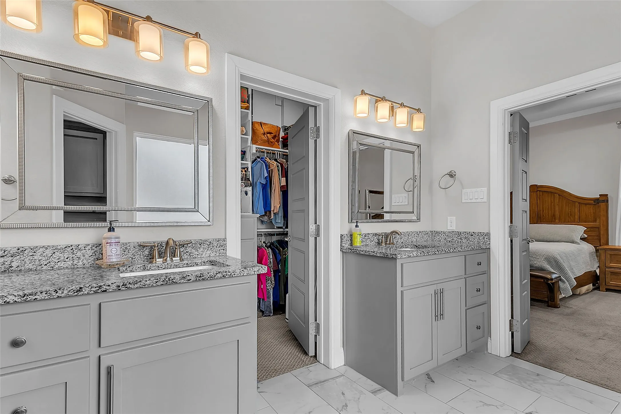 Primary Bathroom Dual vanity area featuring granite countertops, framed mirrors and decorative lighting and tile flooring