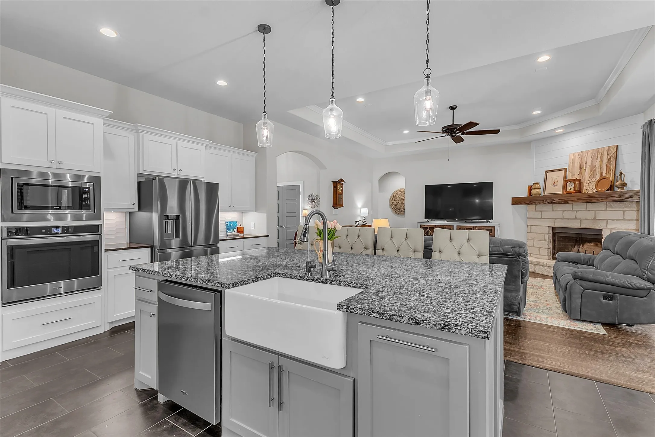 Large kitchen island with a farmhouse sink, granite countertop, and pendant lighting
