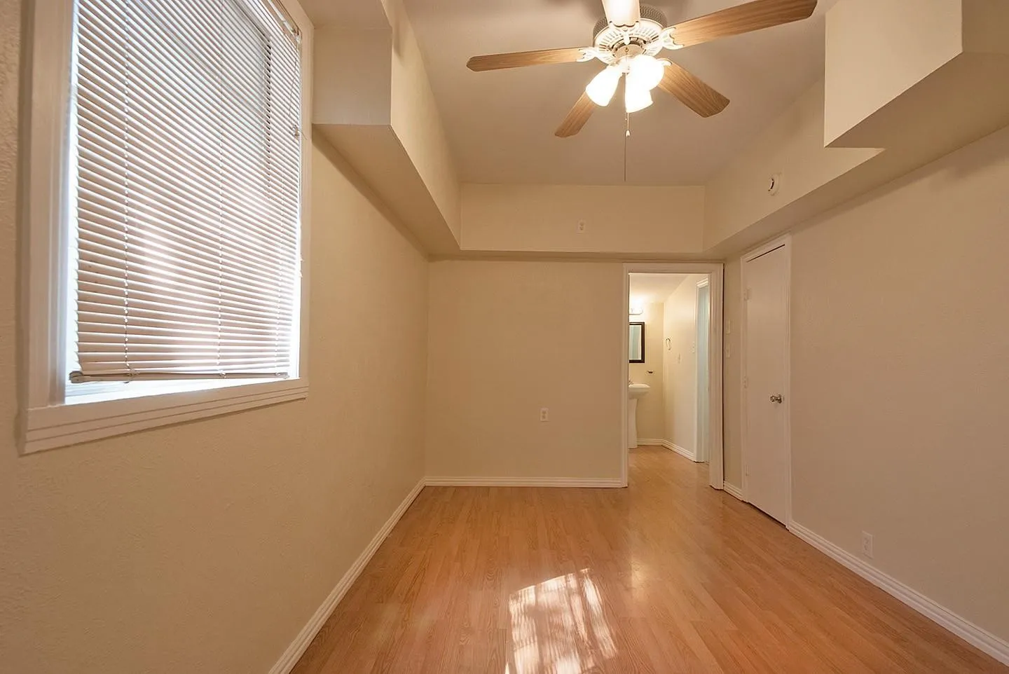 A cozy bedroom with a window featuring hardwood floors and a ceiling fan, perfect for keeping cool and comfortable.