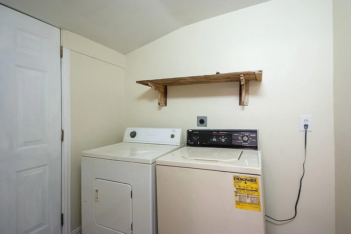 Utility room with a side-by-side washer and dryer, neatly arranged with a shelf above for storage.