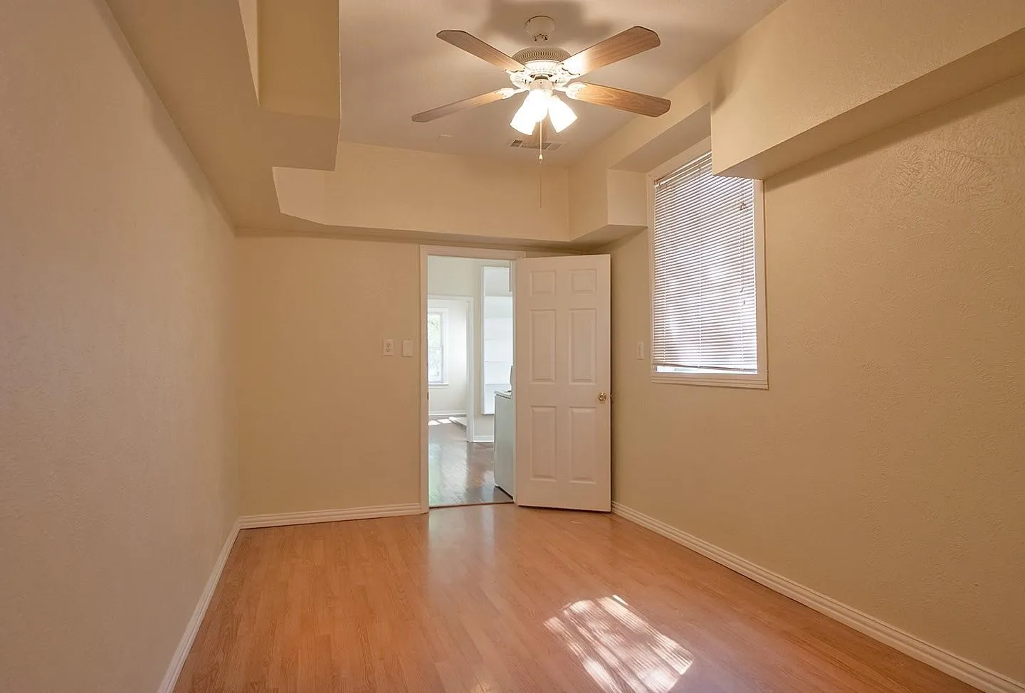 A cozy bedroom with a window featuring hardwood floors and a ceiling fan, perfect for keeping cool and comfortable.