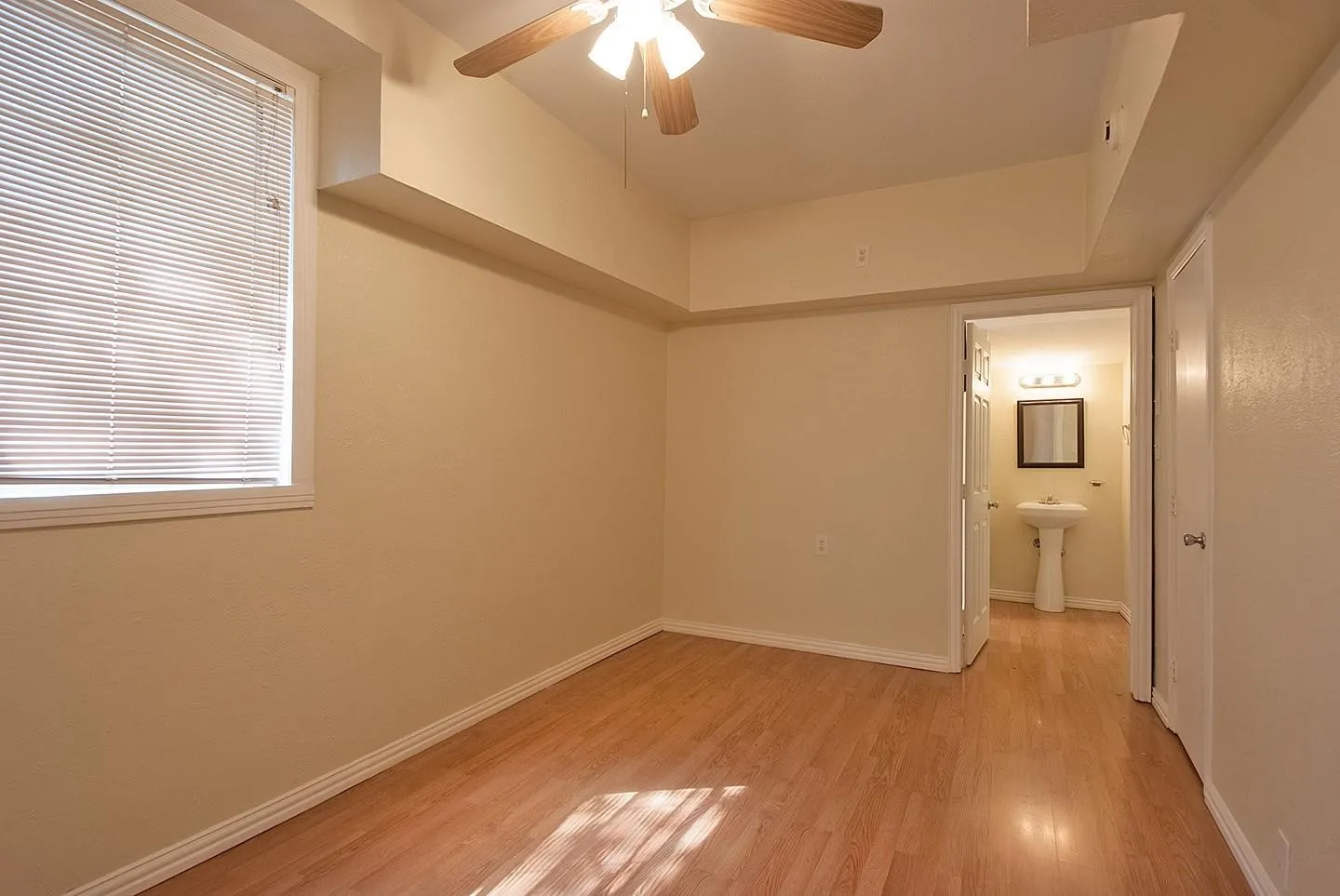 A cozy bedroom with a window featuring hardwood floors and a ceiling fan, perfect for keeping cool and comfortable.