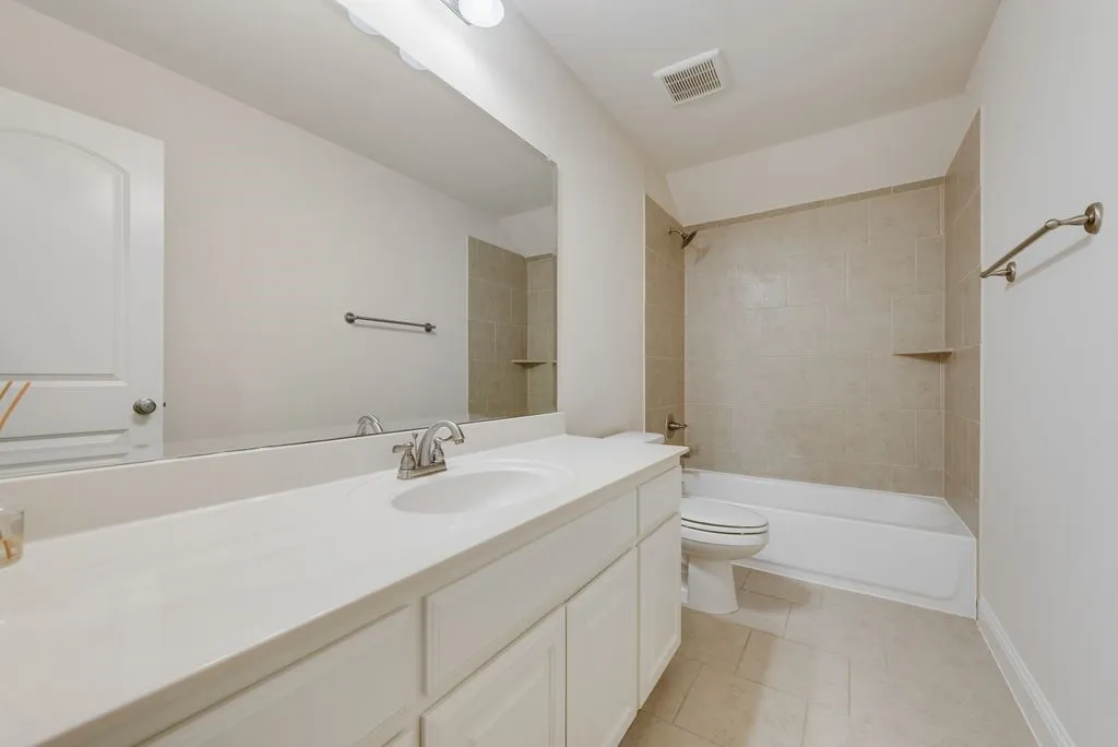 Bathroom featuring a single vanity with an integrated sink, broad wall-mounted mirror, and overhead strip lighting