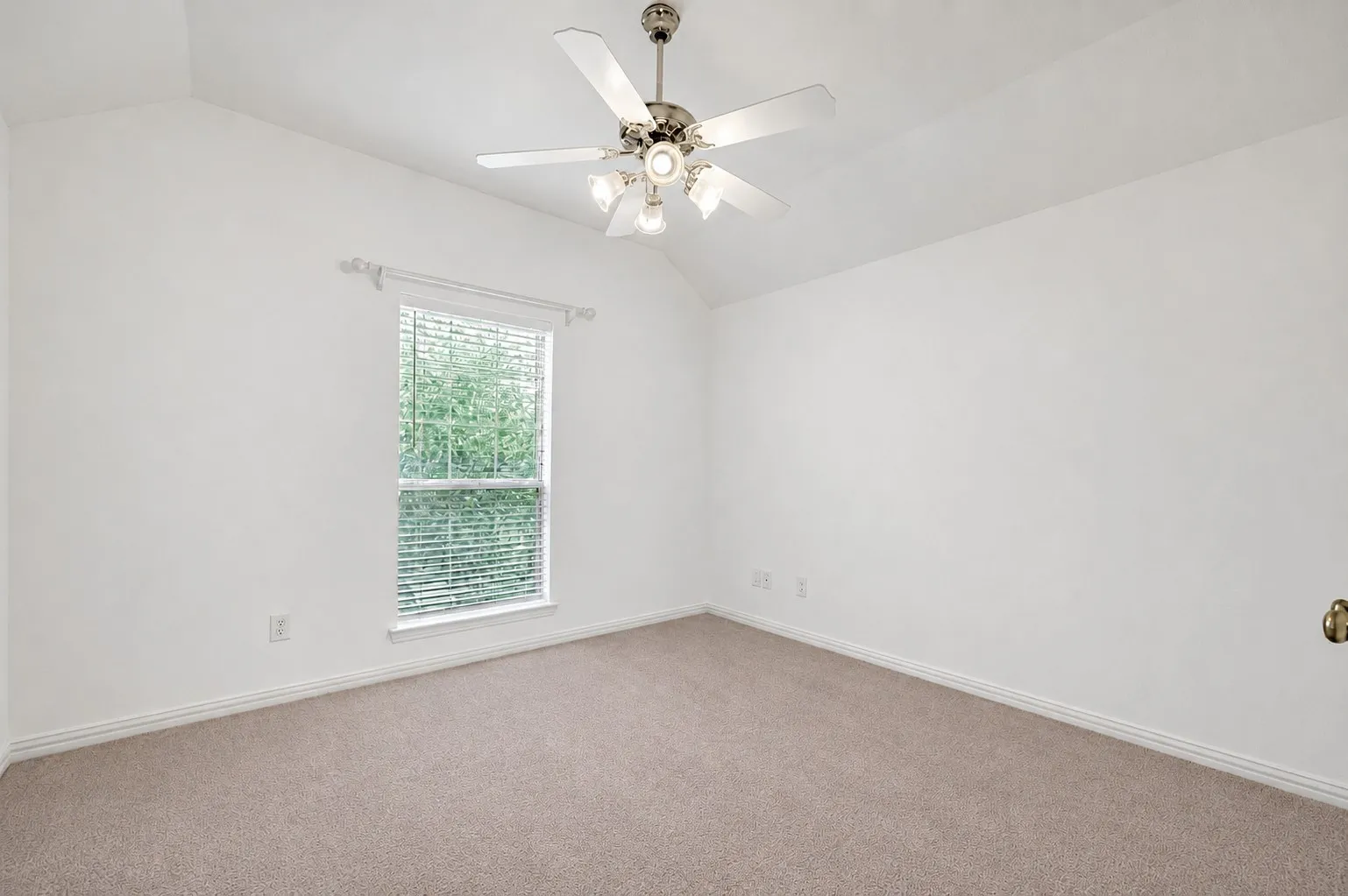 Vaulted ceiling, ceiling fan with light fixture, window with blinds, and neutral carpeting