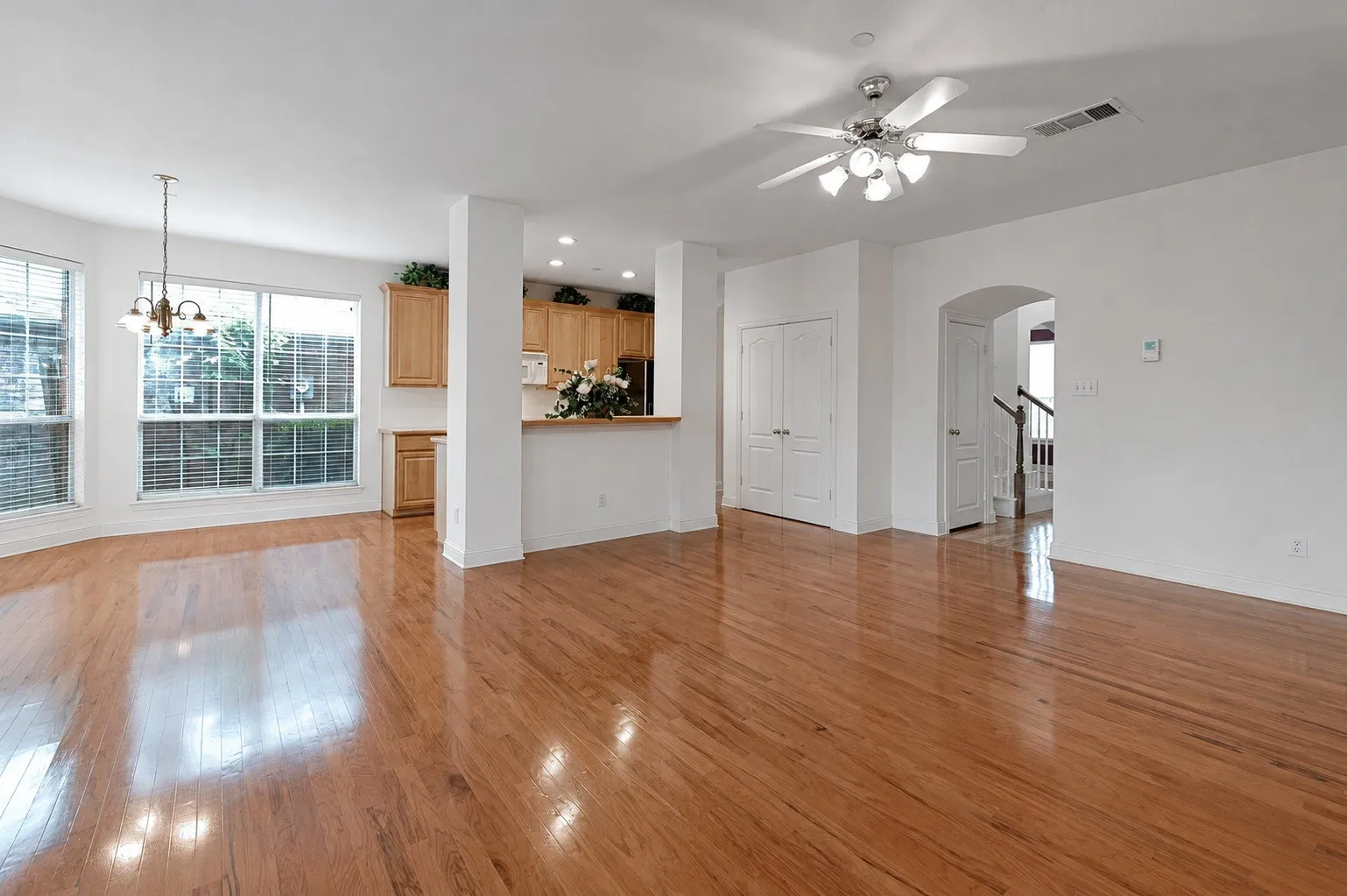 Wood-finish flooring, multiple windows with blinds, recessed lighting, ceiling fan, and arched entryway