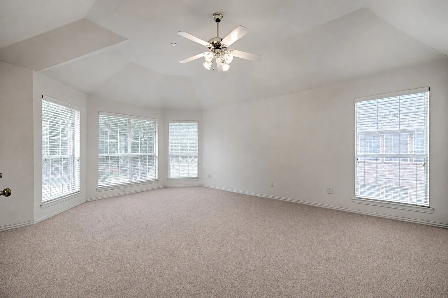 Vaulted ceiling with a ceiling fan, bay window configuration, and carpeted flooring