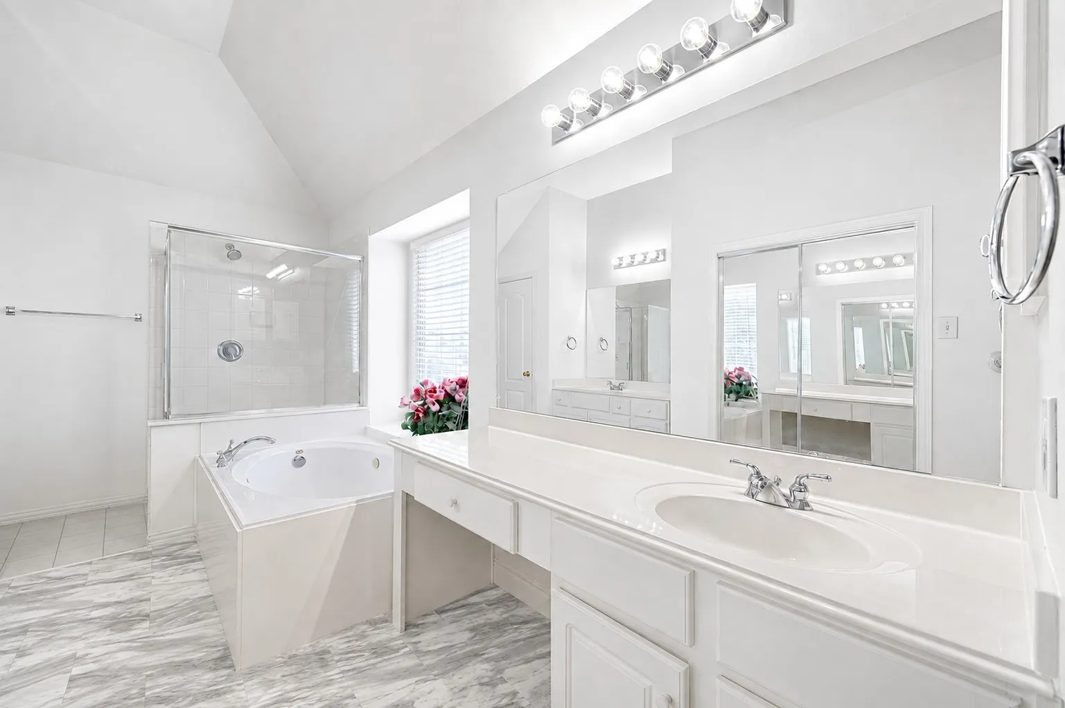 Vaulted ceiling bathroom featuring a built-in jetted tub, glass-enclosed shower, dual vanity with integrated sinks, and a large wall-mounted mirror