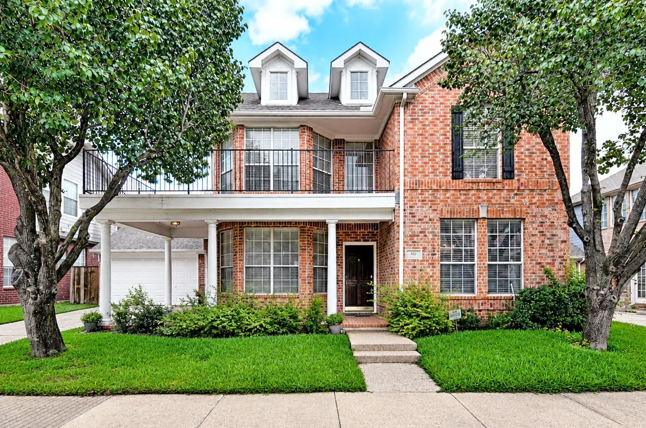 Traditional brick exterior with white trim, featuring a second-story balcony with iron railing