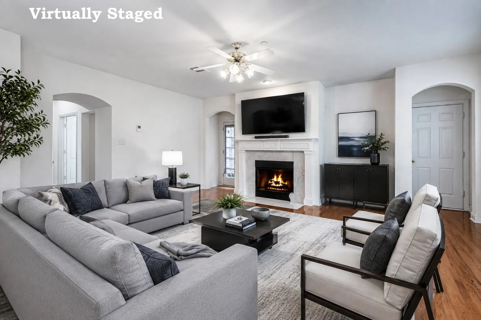 Living area featuring wood-finish flooring, a fireplace with a stone surround and mantel, arched doorways, a ceiling fan, and recessed lighting