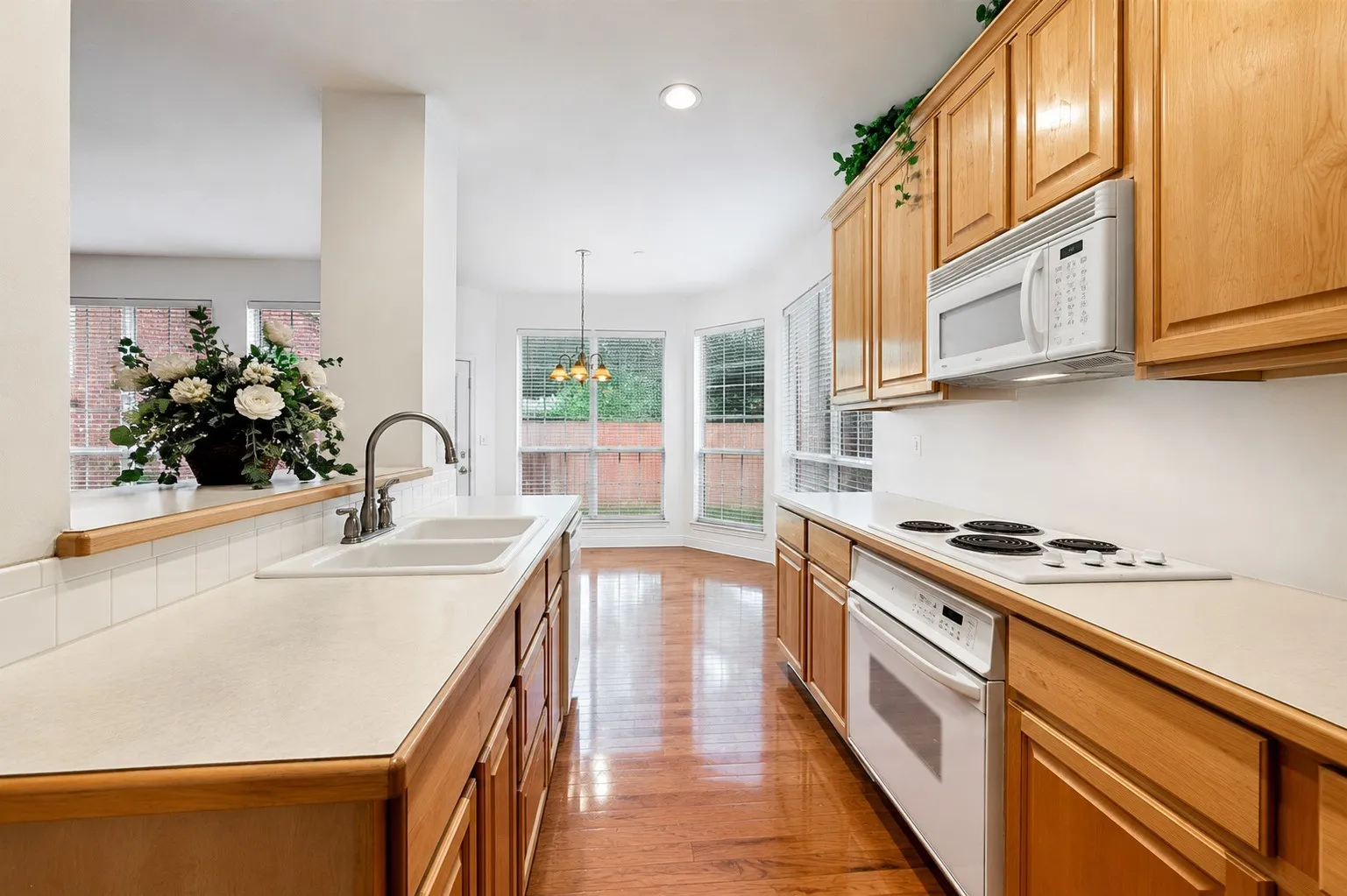 Kitchen featuring wood-finish cabinetry, a double basin sink, and a built-in microwave and oven