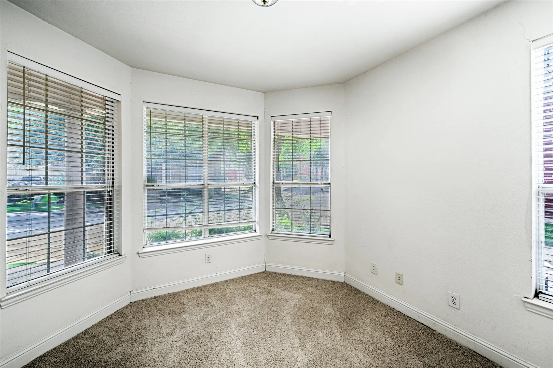 Bay window featuring three large windows with horizontal blinds and white trim
