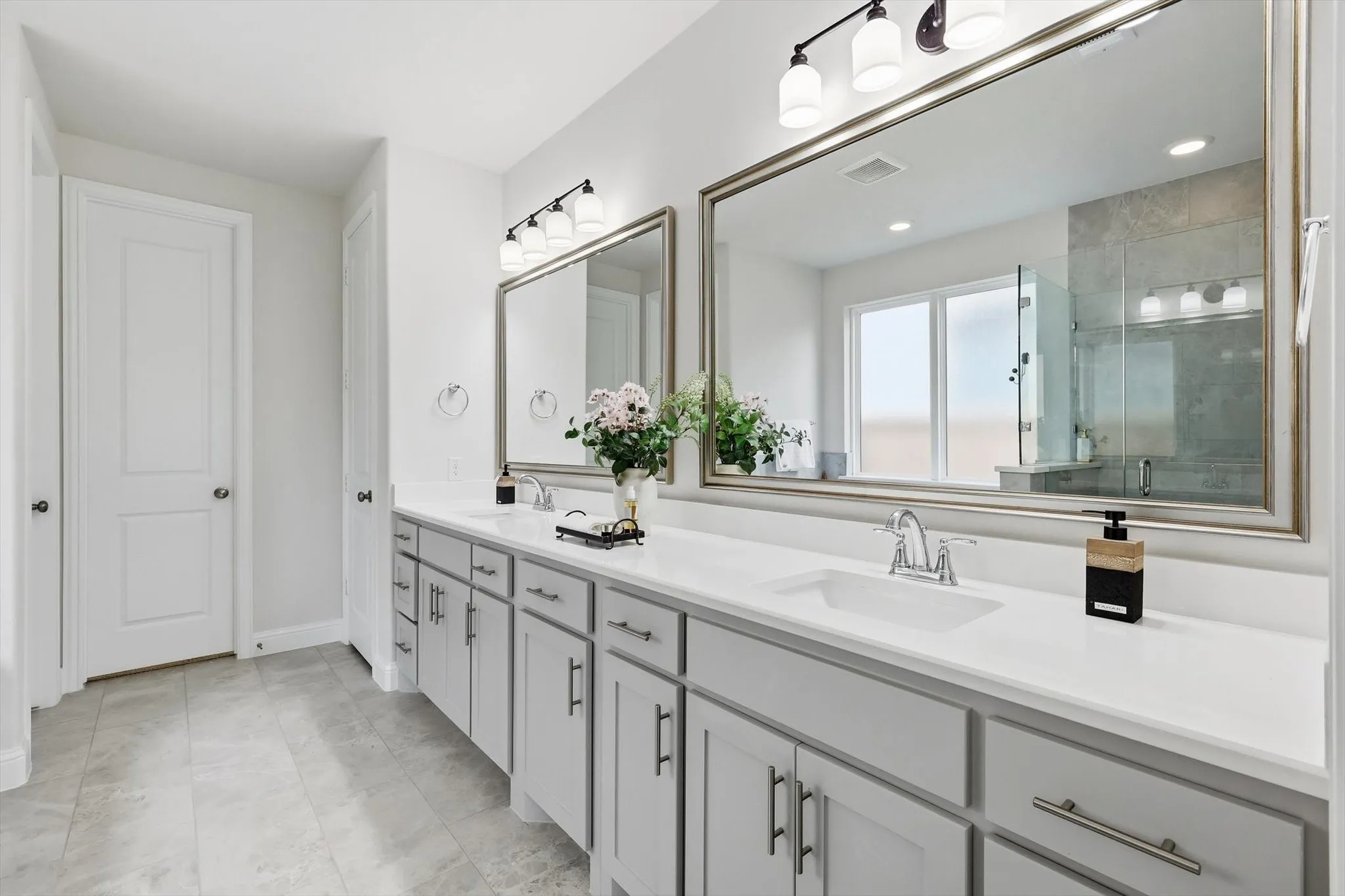 Spacious bathroom featuring a dual vanity with light gray cabinetry, white countertops, and undermount sinks