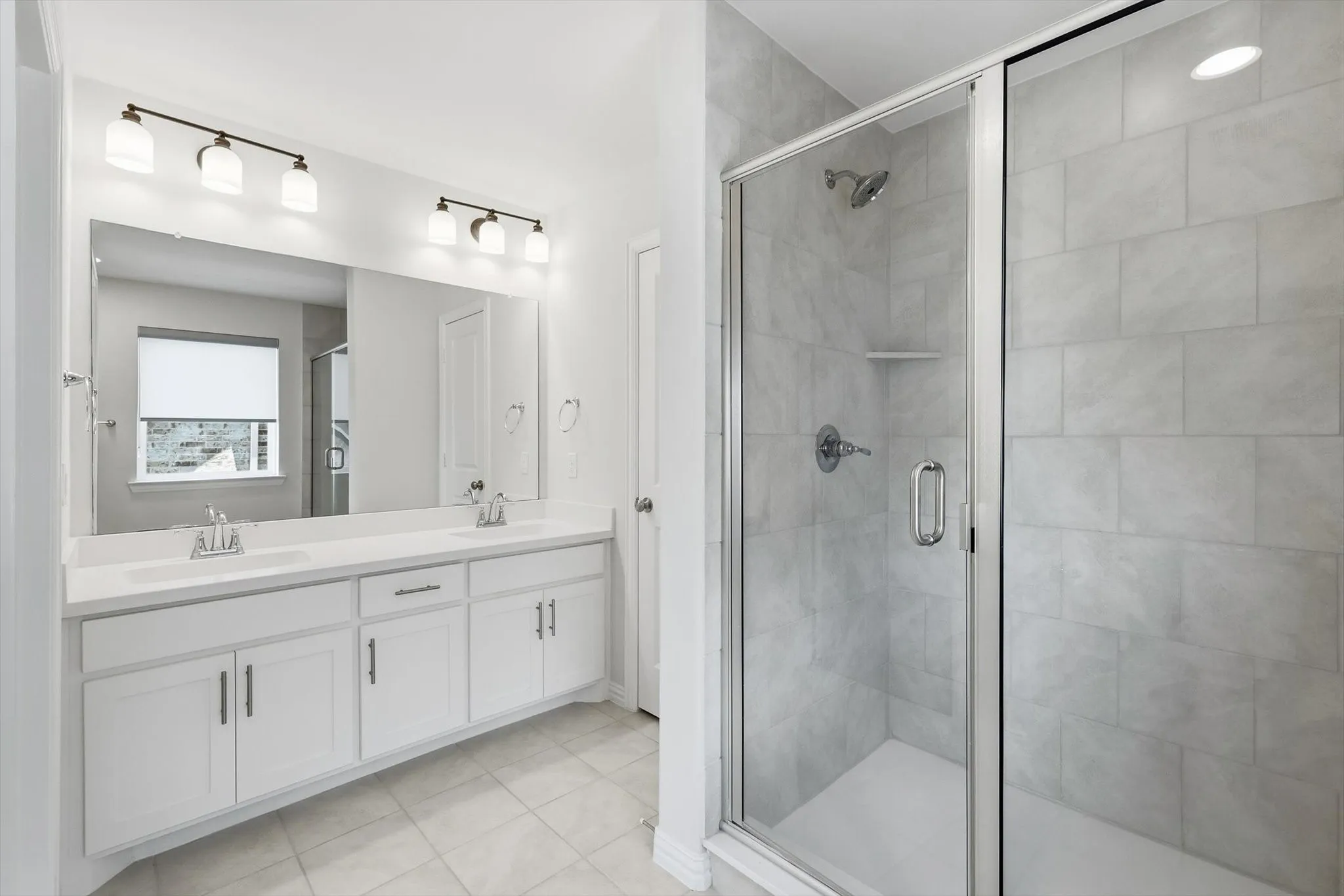 Bathroom featuring a dual vanity with white cabinetry, white countertops, and a large mirror
