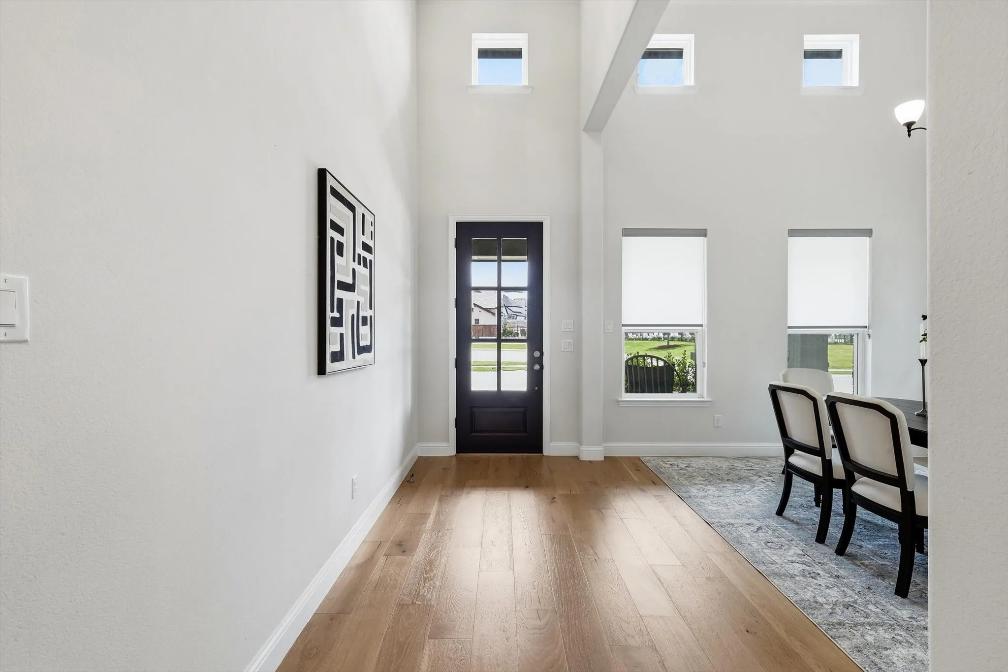 Entryway featuring wood-finish flooring, a dark-paneled door with glass inserts, and high ceilings