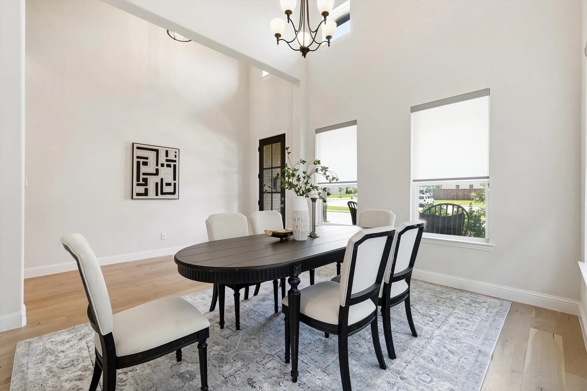 Dining space featuring high ceilings, light wood-finish flooring, and white walls