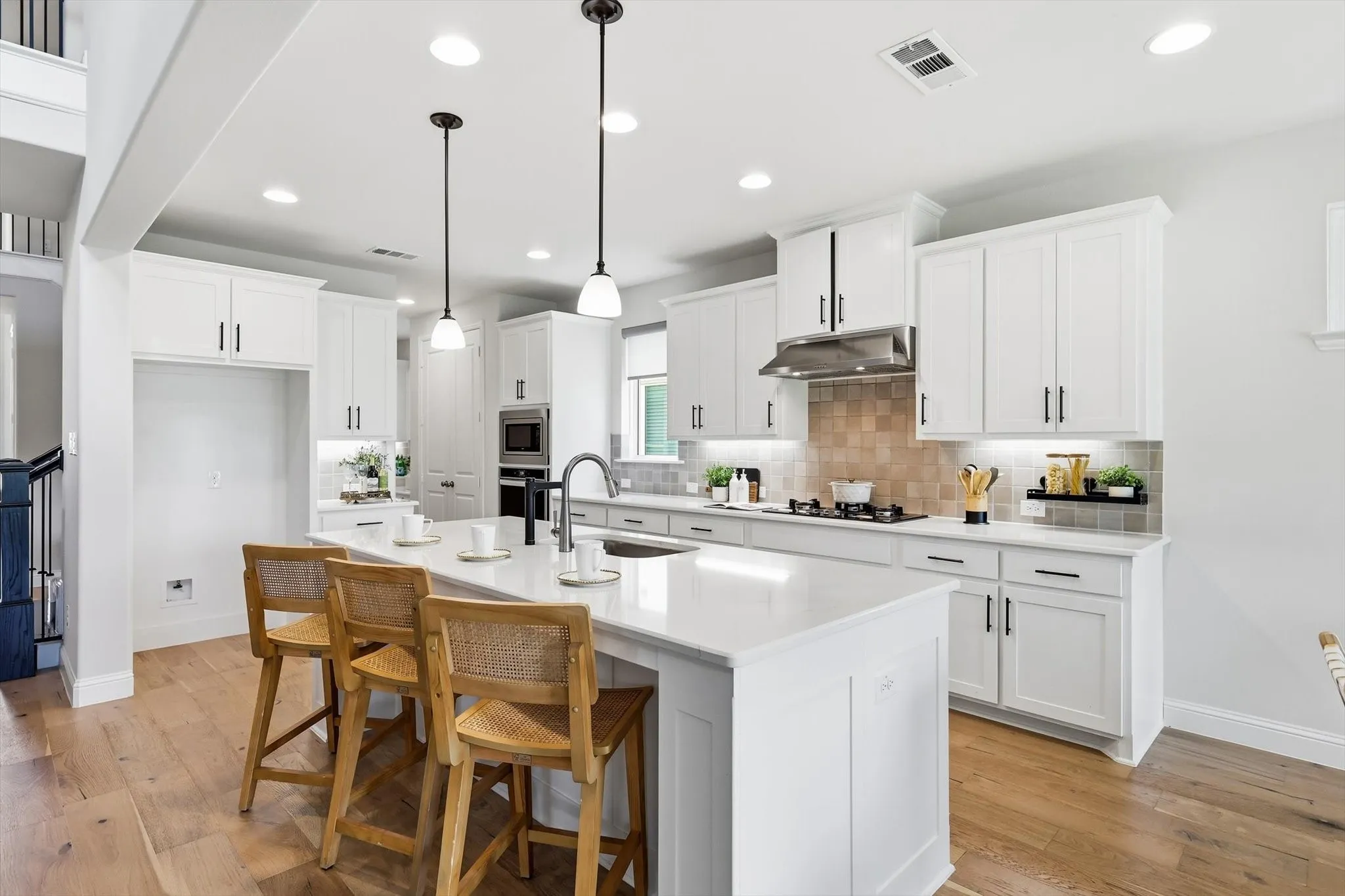 Gourmet kitchen featuring a large central island with seating, white shaker cabinetry, stainless steel appliances, a tiled backsplash, and recessed lighting