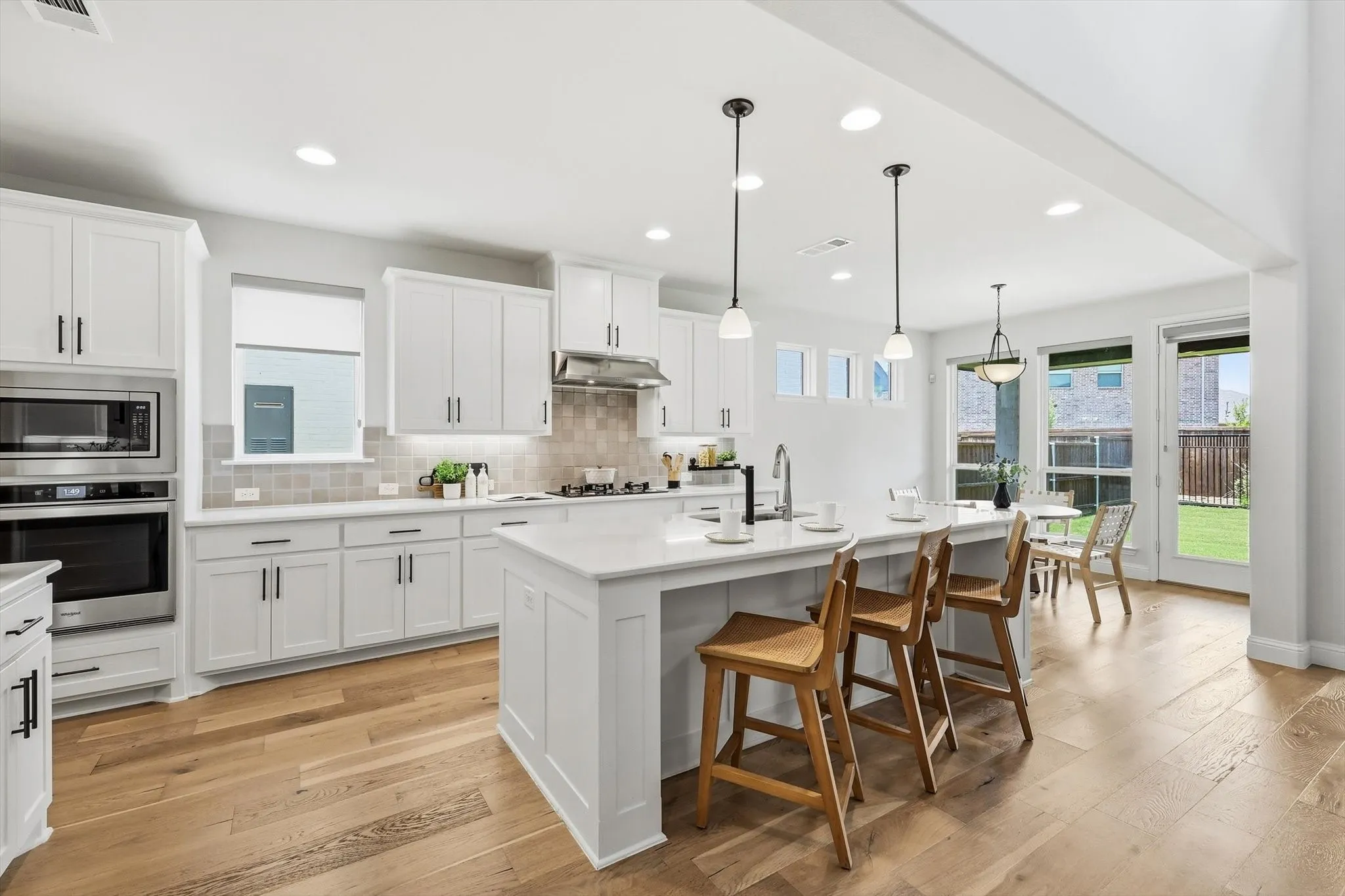 Kitchen featuring a central island with bar seating, stainless steel appliances, white cabinetry, light wood-finish flooring, and recessed lighting