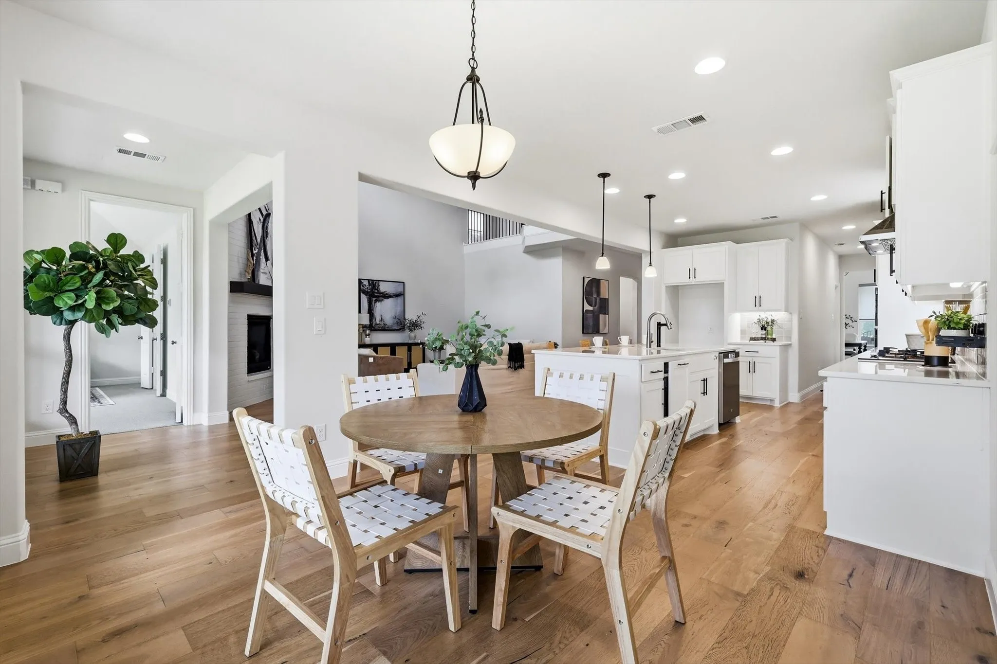 Spacious dining area with wood-finish flooring, featuring an open-concept design that incorporates a contemporary kitchen