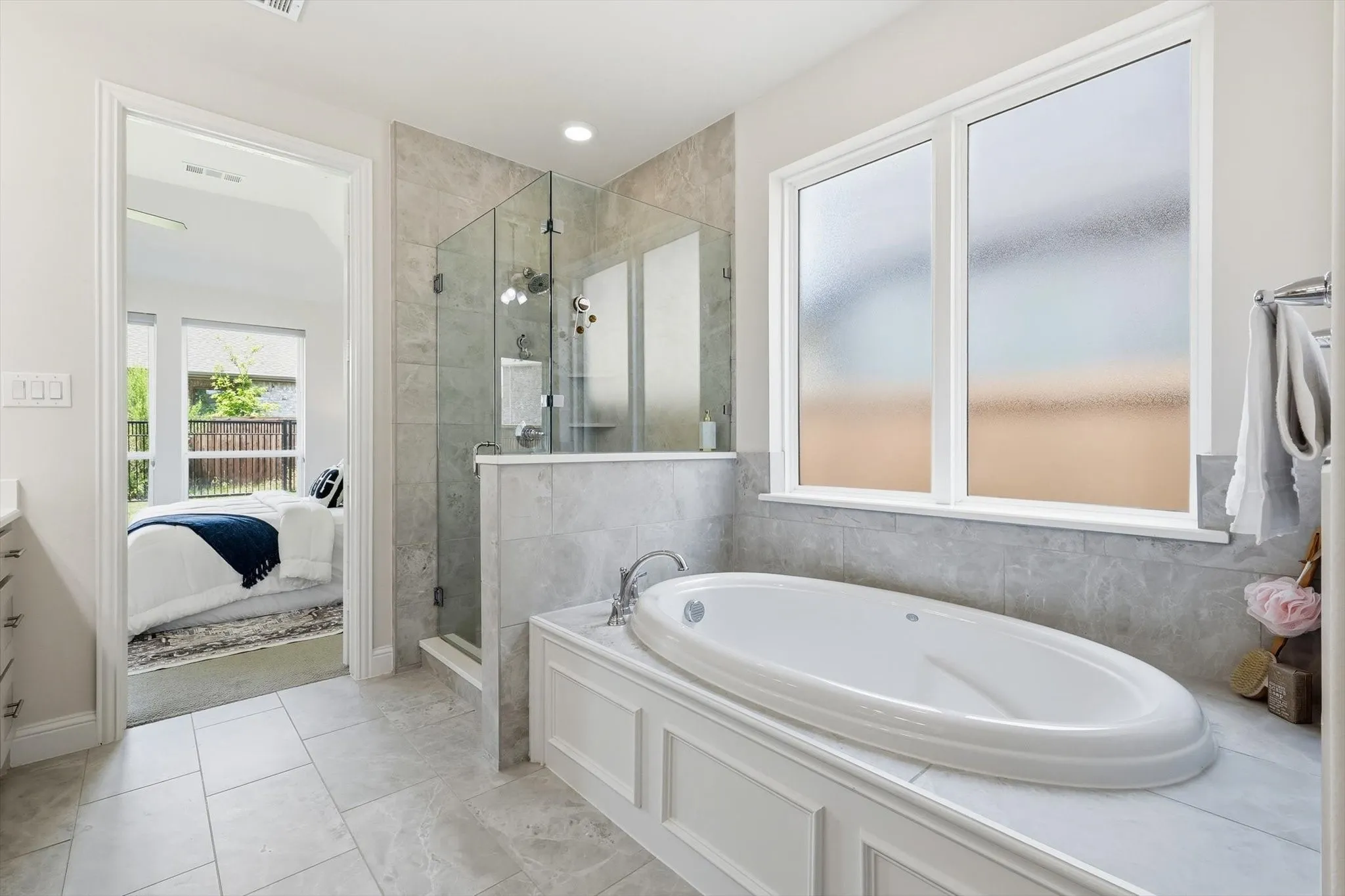 Contemporary bathroom featuring a large soaking tub with decorative paneling, a frameless glass shower enclosure, and a frosted window