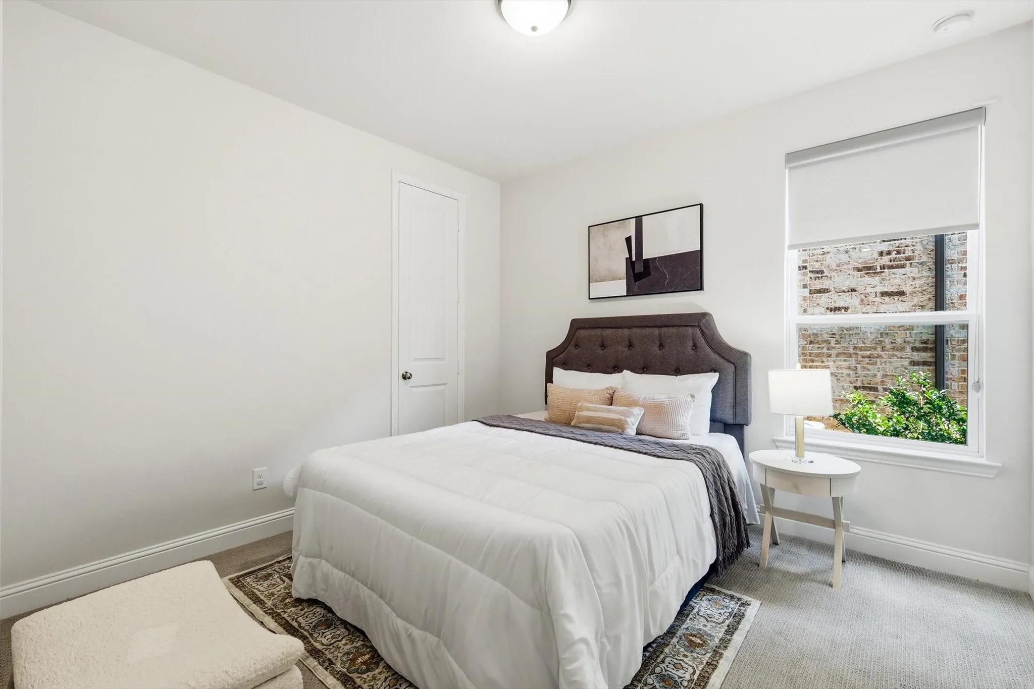 Bright room featuring a large window, neutral carpet flooring, white walls, and a white paneled door