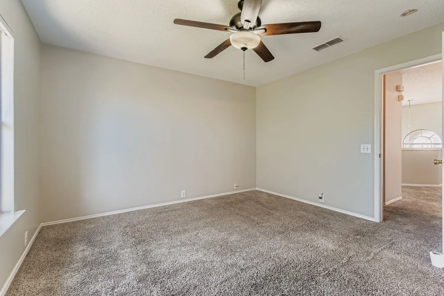 Carpeted room with neutral wall paint and a ceiling fan with integrated lighting