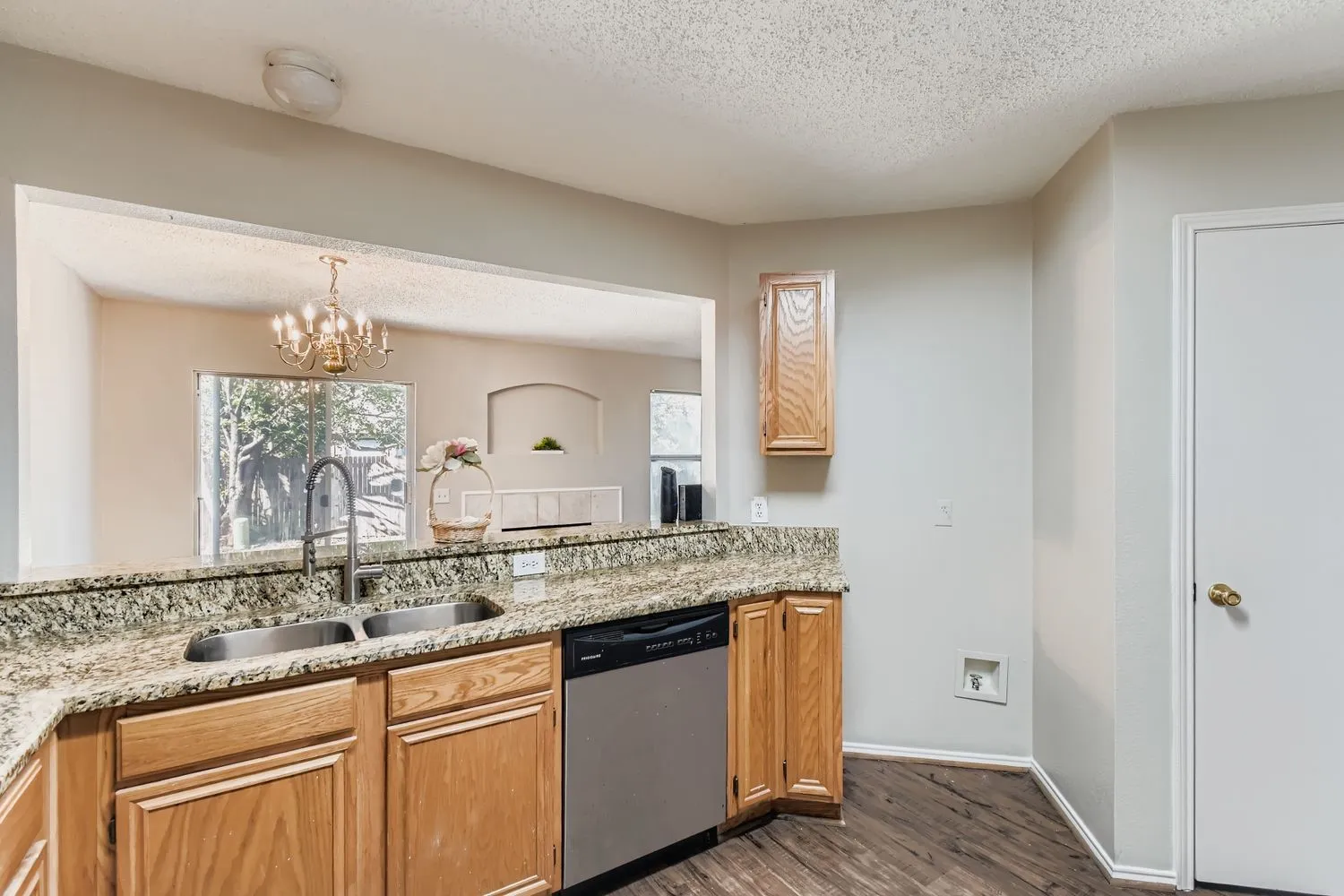 Kitchen featuring wood-finish cabinetry, granite countertops, stainless steel double basin sink, and a stainless steel dishwasher