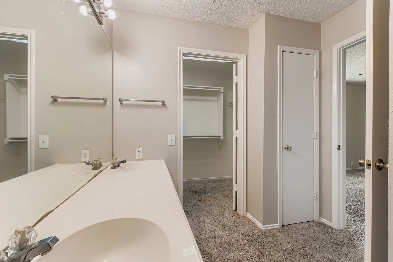 Bathroom vanity with dual integrated sinks, an expansive wall-mounted mirror, and vanity lighting