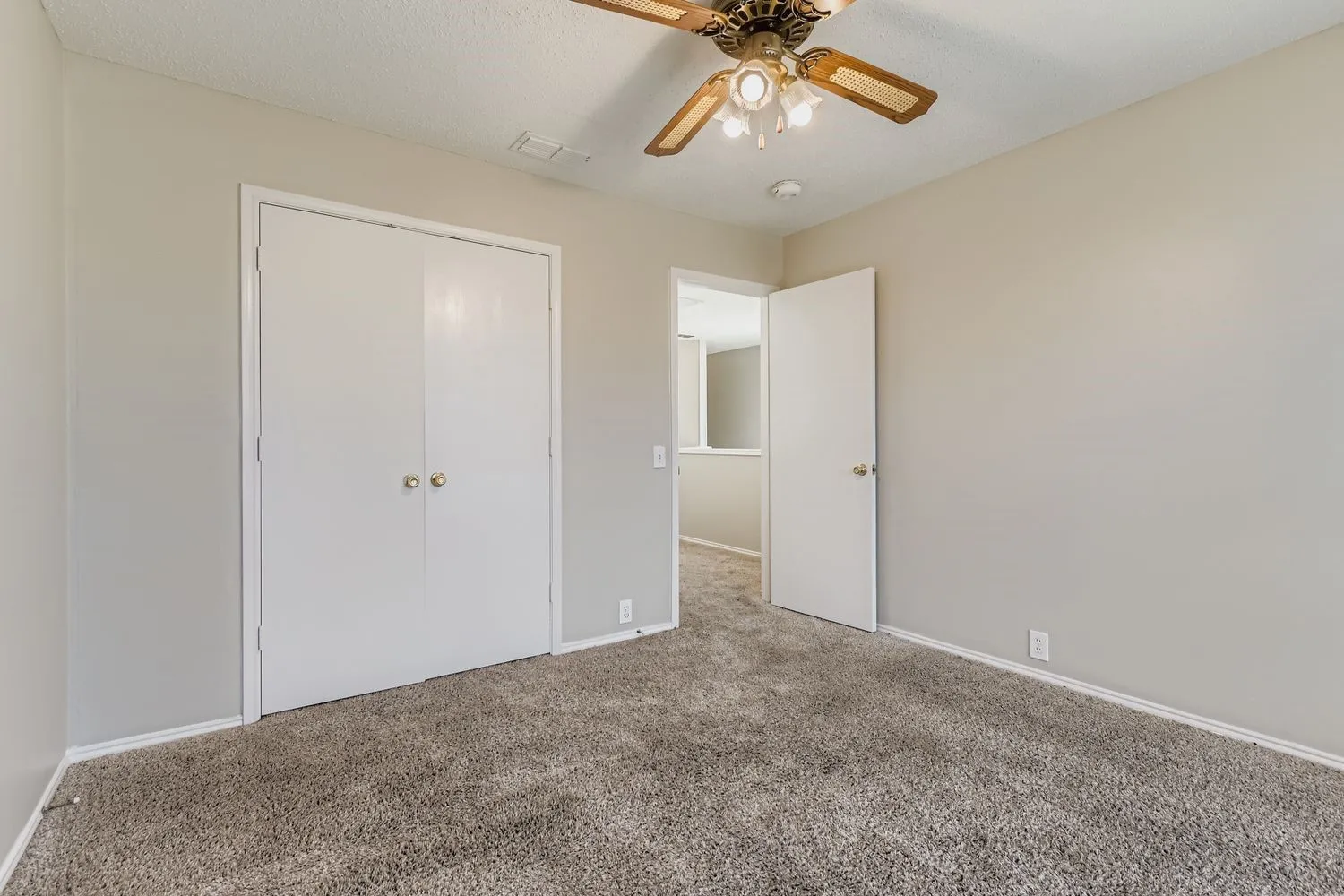 Neutral tone wall paint, textured carpet flooring, bi-fold closet doors, and a ceiling fan with integrated lighting