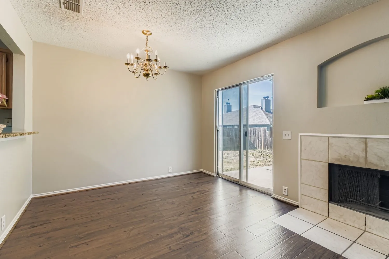 Spacious room featuring wood-finish flooring, a contemporary chandelier, and direct outdoor access via sliding glass doors