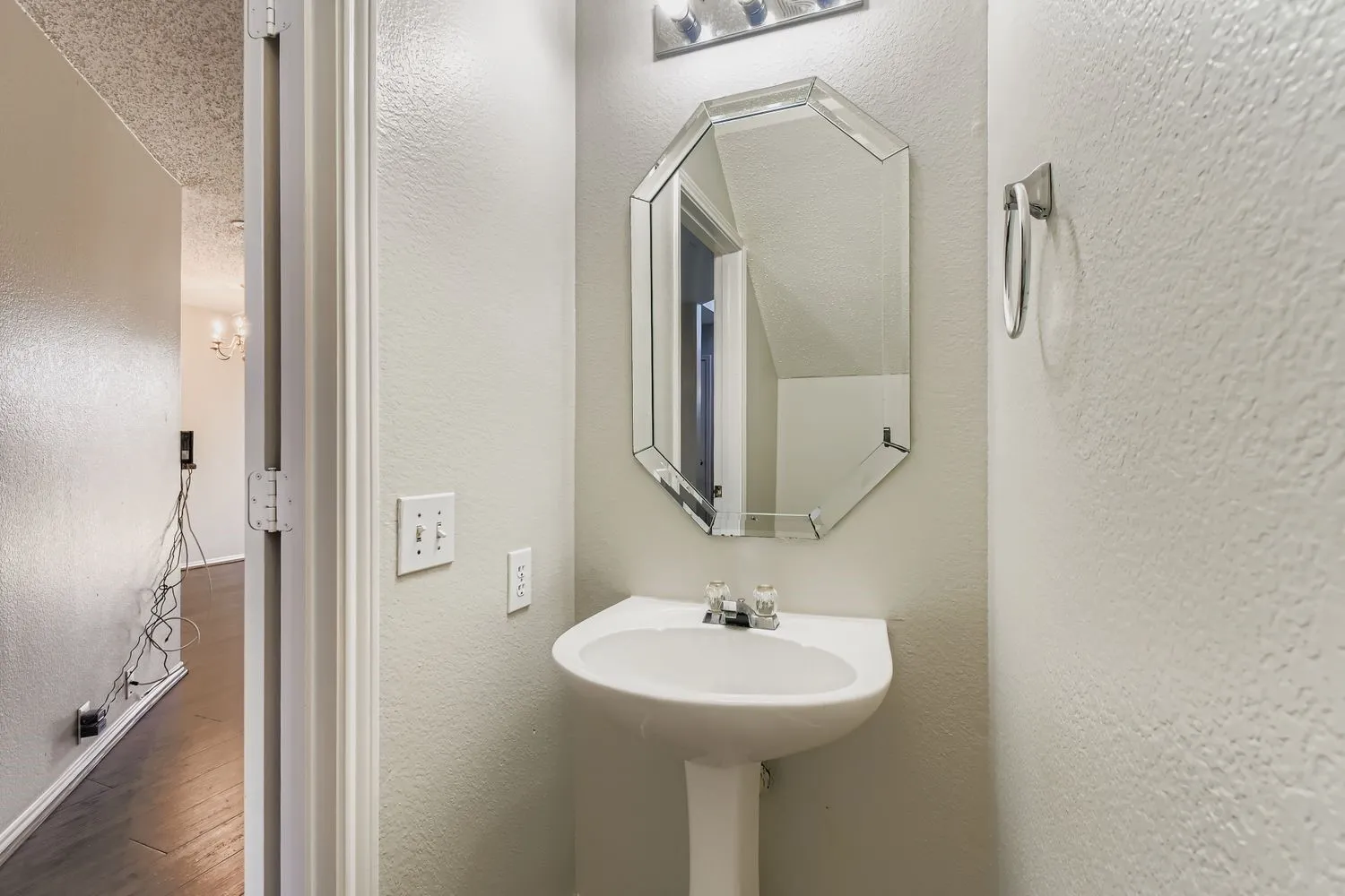 Pedestal sink with chrome faucet hardware, set beneath an octagonal mirrored vanity
