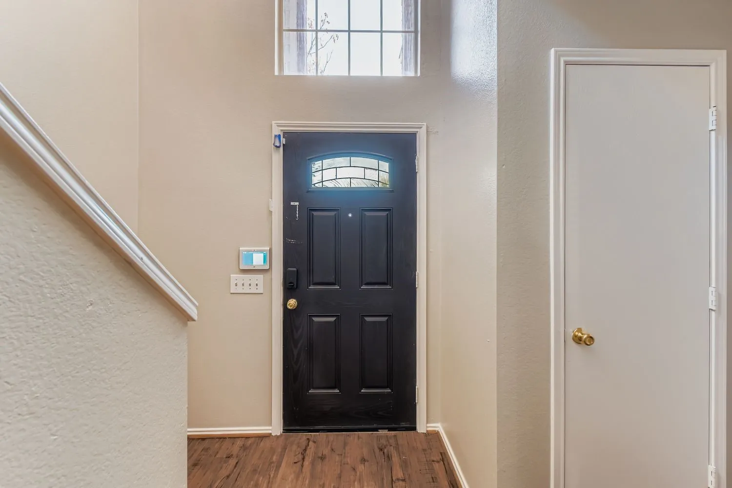 Entryway featuring a paneled black door with an arched decorative glass insert and a transom window