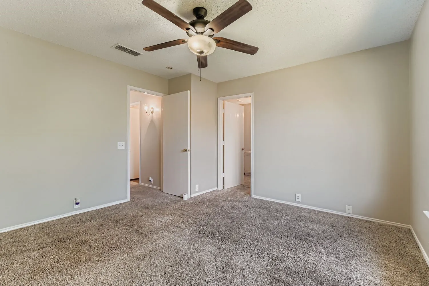 Spacious room with plush carpeting and light neutral wall paint