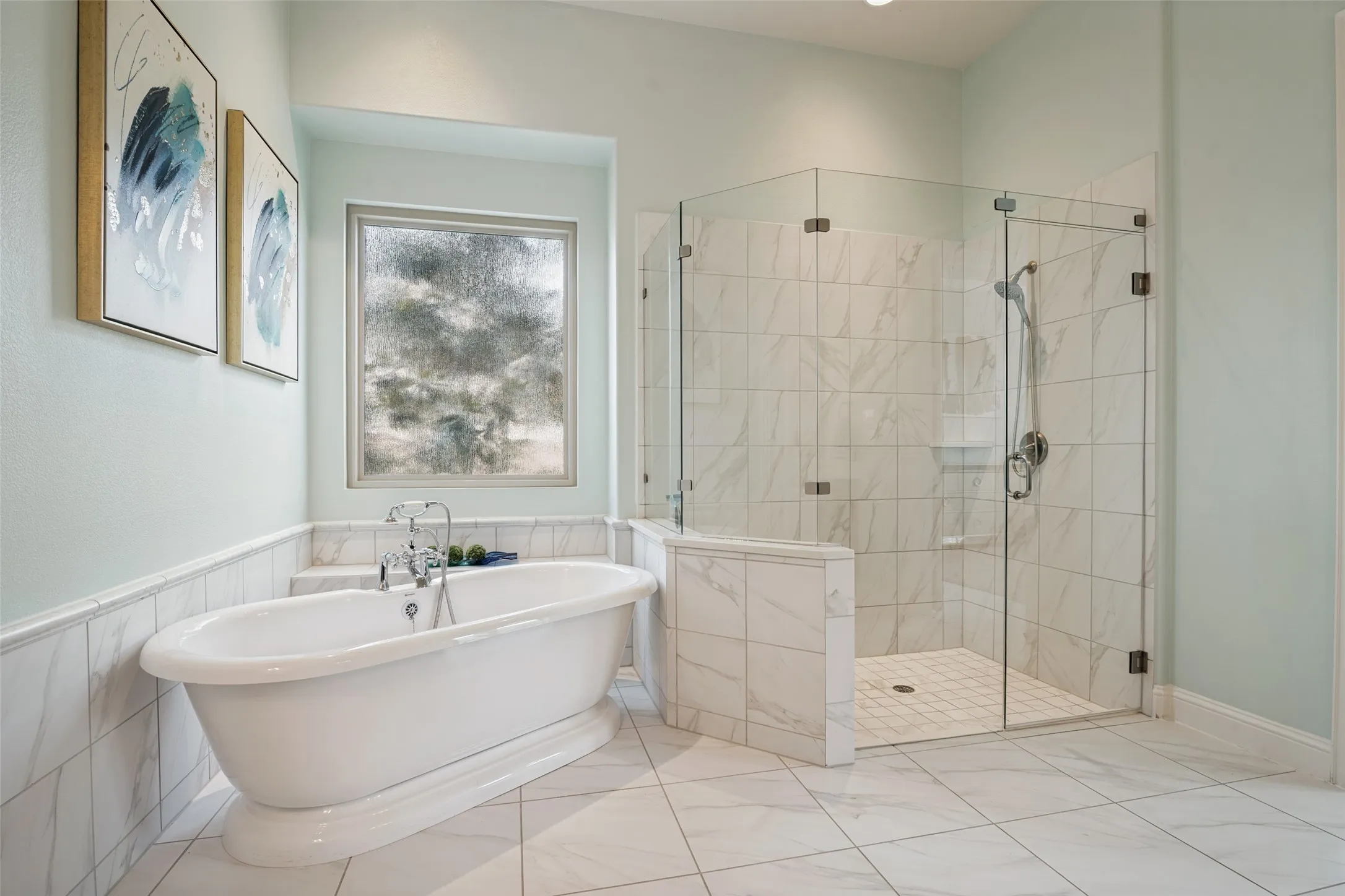 Spacious bathroom featuring a freestanding soaking tub with chrome fixtures, a large glass-enclosed shower, and extensive tile flooring
