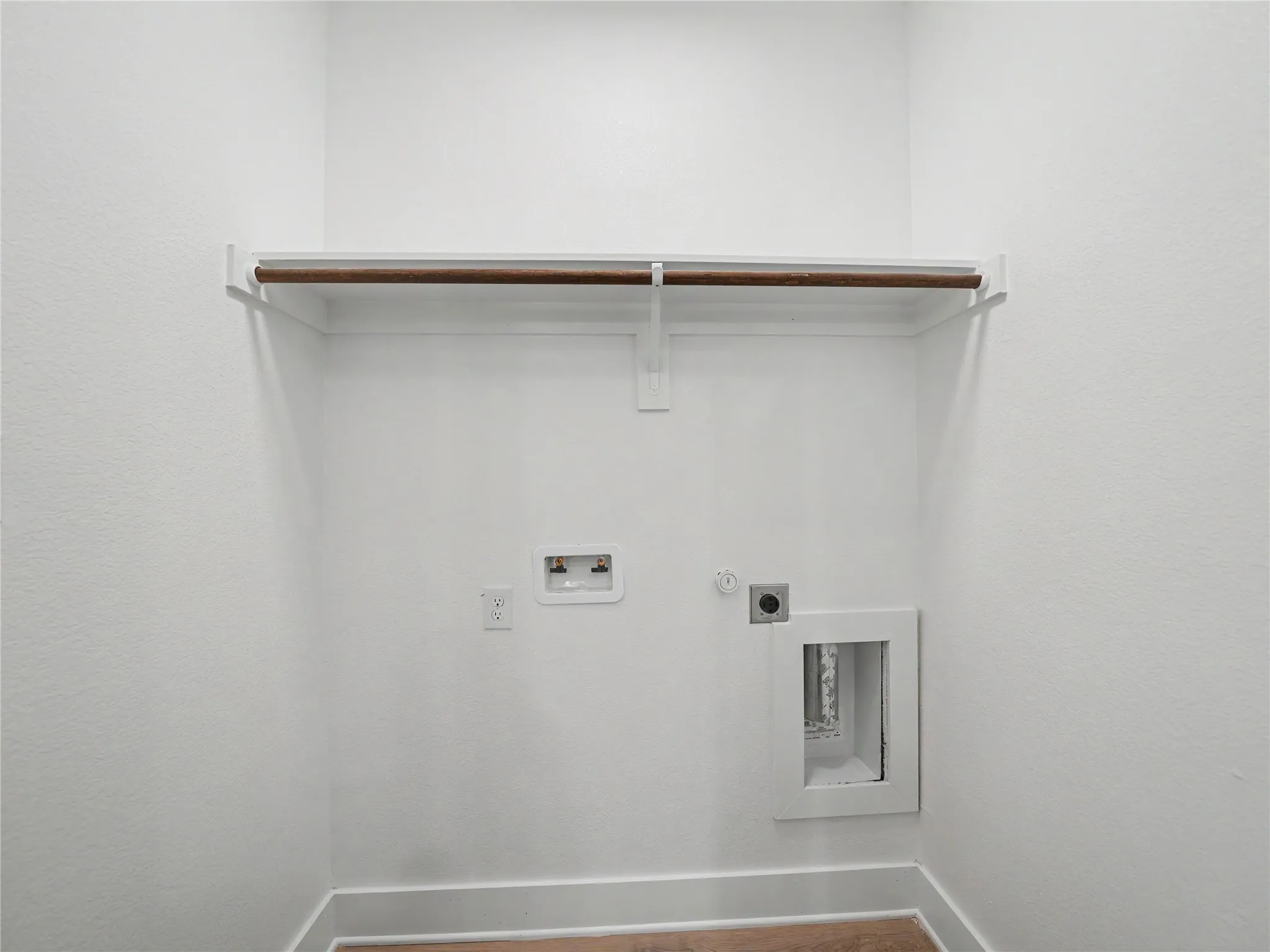 Dedicated laundry space with wood-finish flooring and a clothing rod