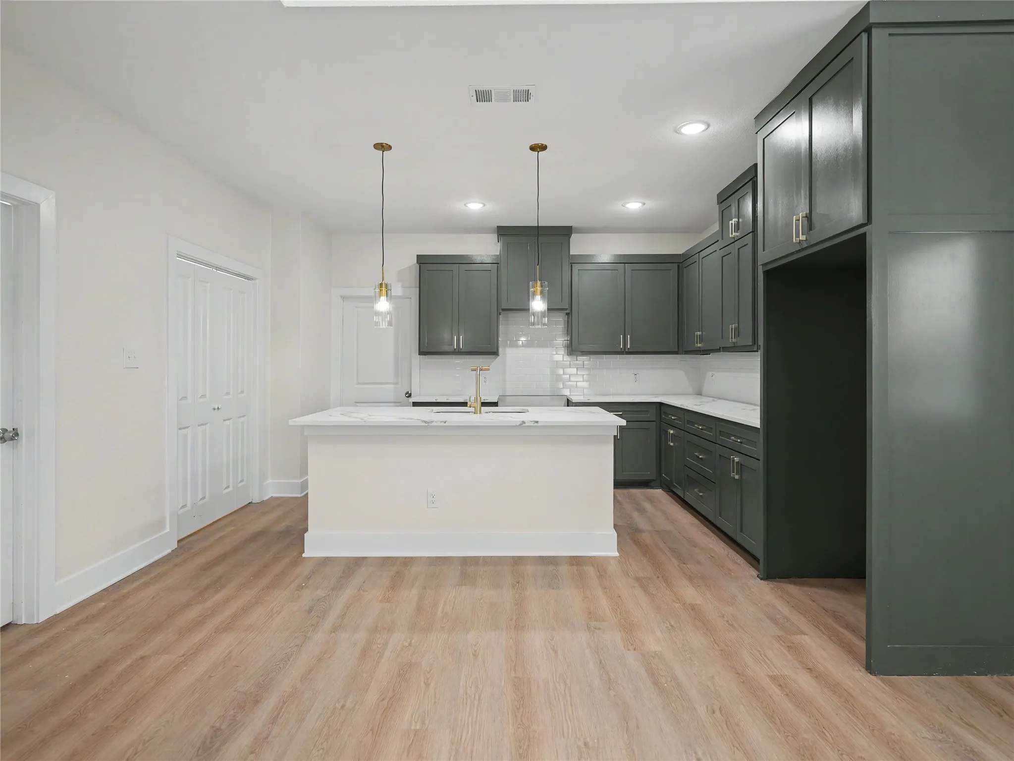 Contemporary kitchen featuring dark green cabinetry, white countertops, and a subway tile backsplash