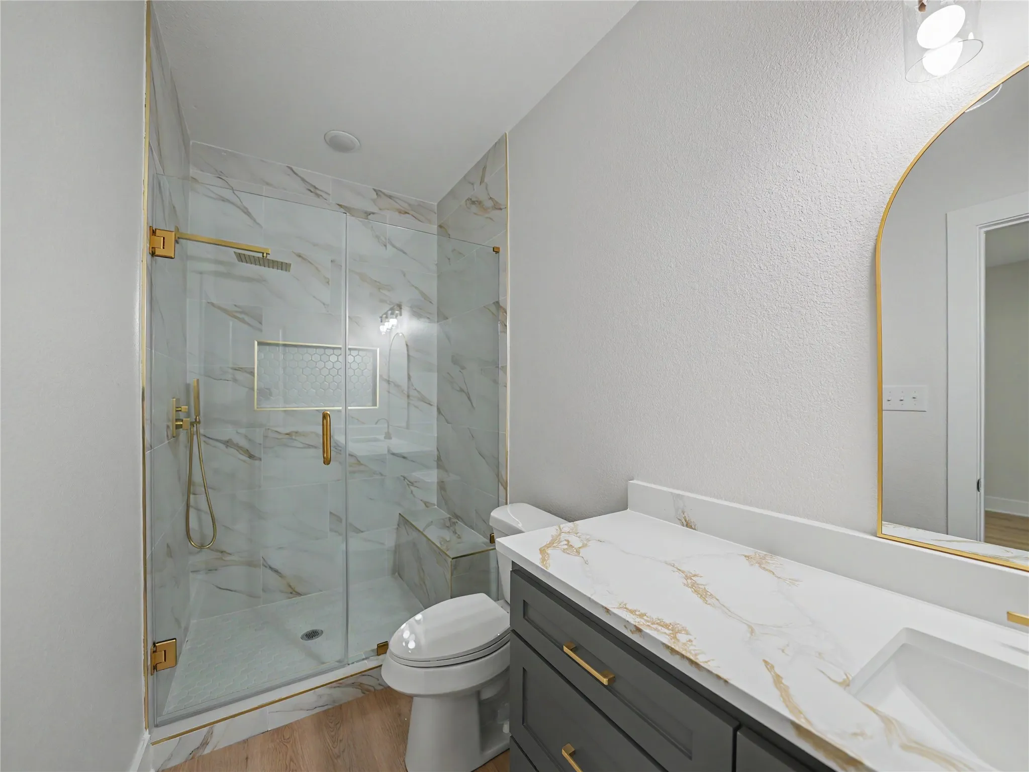 Walk-in shower with gold-finish fixtures and patterned wall tile