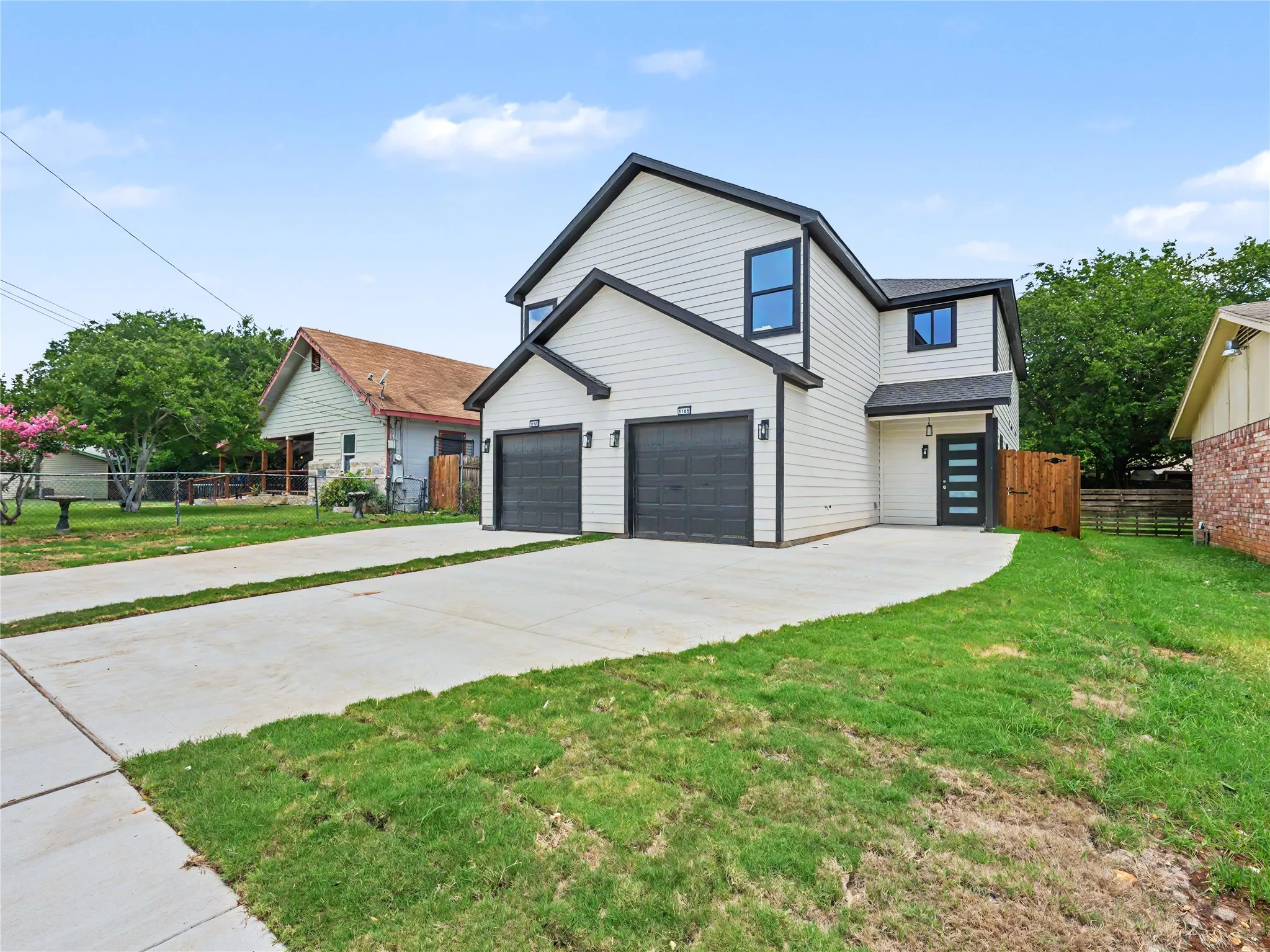 Modern two-story residence featuring white siding with dark trim accents, a two-car garage, and a contemporary front entry door