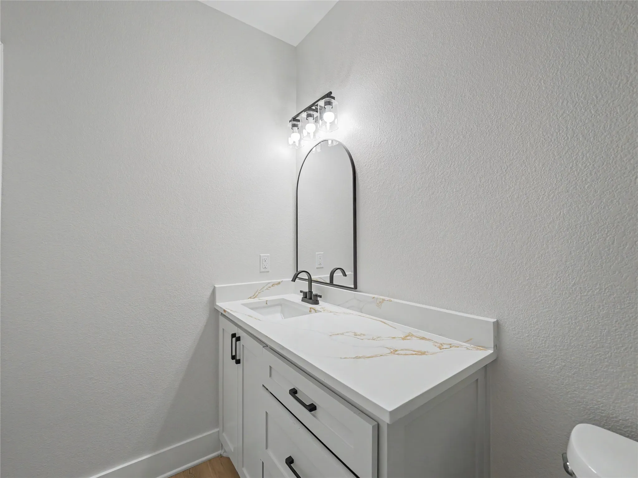 White vanity featuring shaker-style cabinetry, a white countertop with gold veining, and a rectangular undermount sink