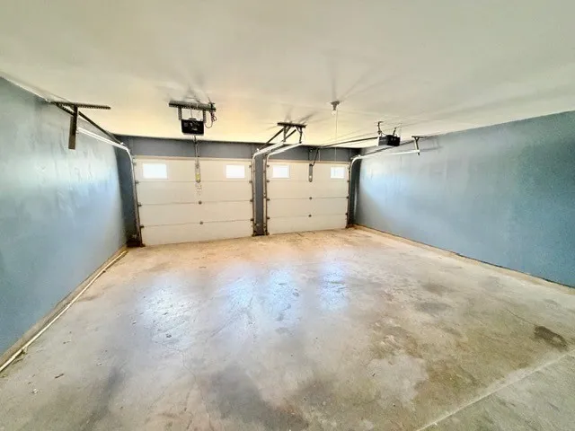 Two-car garage featuring concrete flooring, painted walls, and overhead garage door openers