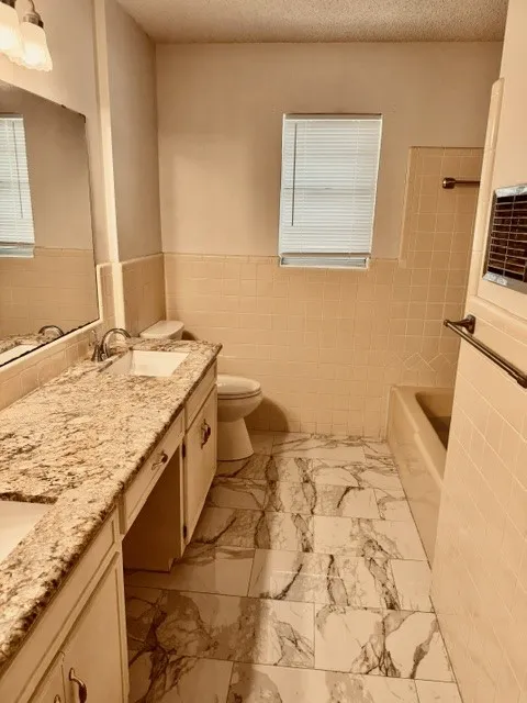Double vanity with an integrated sink, granite-finish countertop, and decorative light fixture