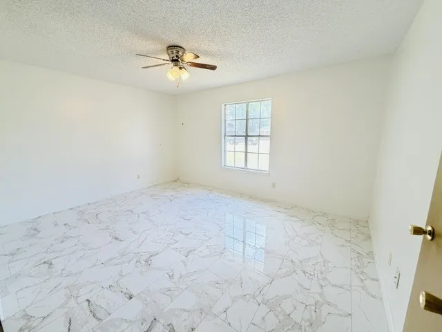 Spacious room featuring white walls and a ceiling fan with integrated lighting