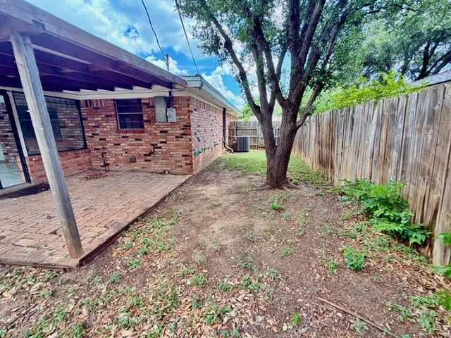 Brick exterior with an expansive patio featuring a covered area, wood beam supports, and brick paving