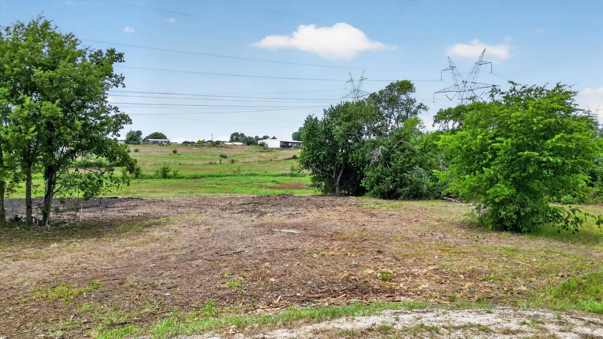 Expansive open land featuring a combination of grassy areas and cleared sections, offering diverse terrain
