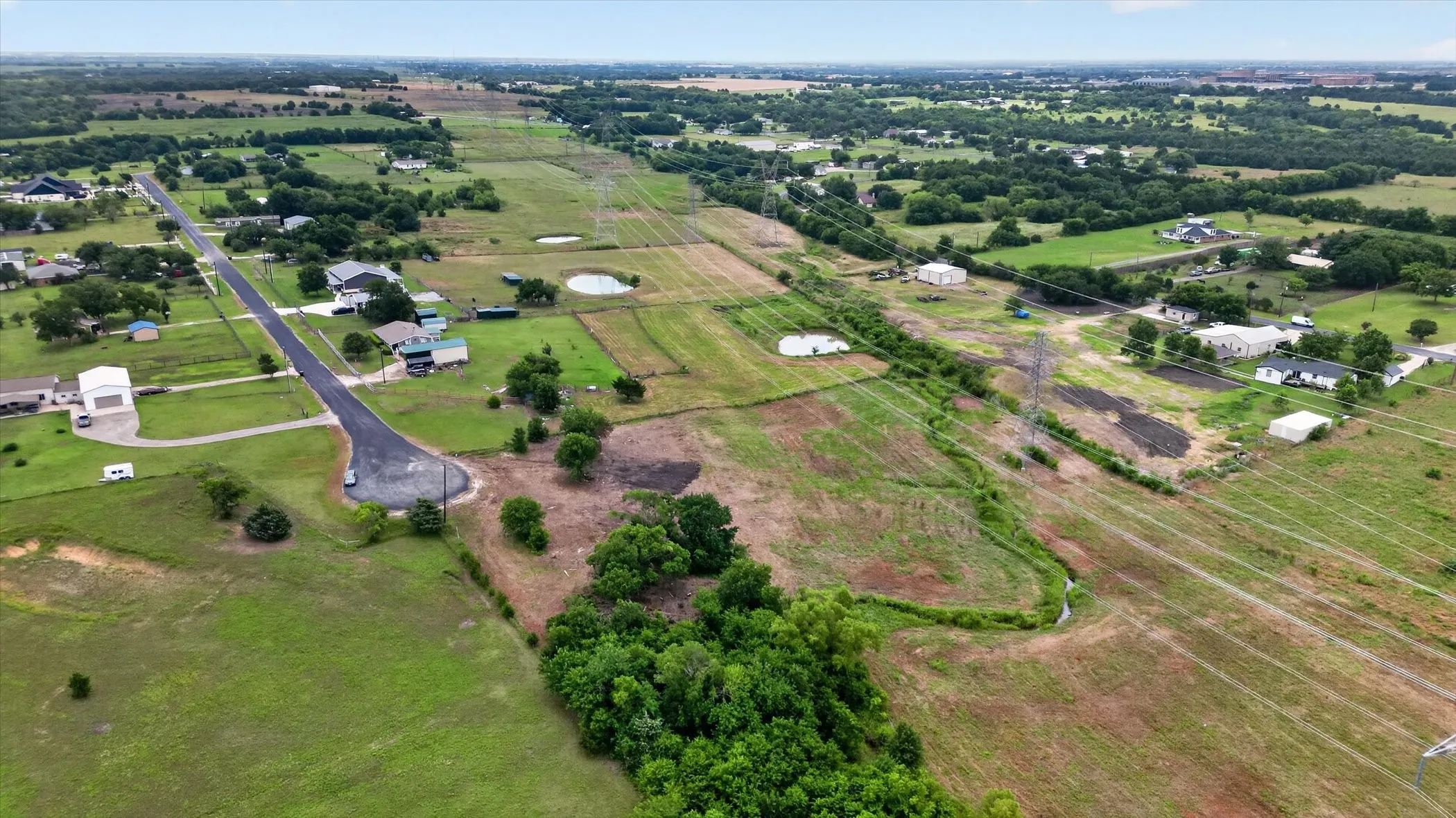 Expansive rural landscape featuring a cul-de-sac, scattered residential properties, mature trees, and a pond