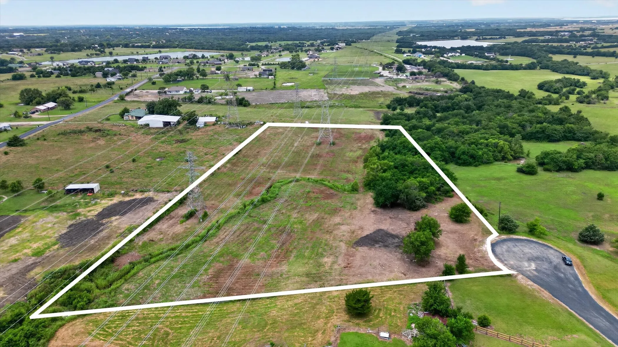 Expansive undeveloped land featuring a mix of cleared areas and mature trees, a natural stream, and direct access to a paved cul-de-sac