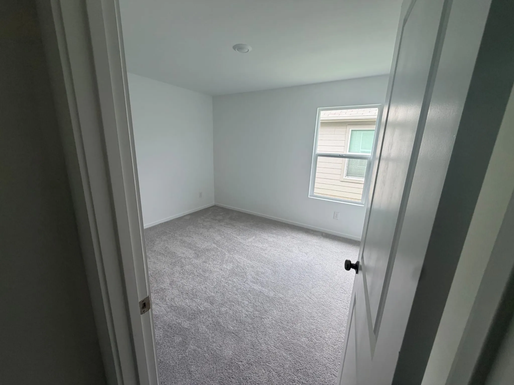 Neutral-toned room featuring a single window and recessed lighting