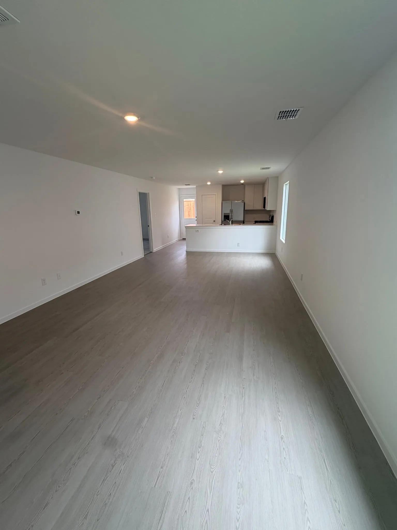 Open-concept living area featuring light wood-finish flooring, recessed lighting, and crisp white walls