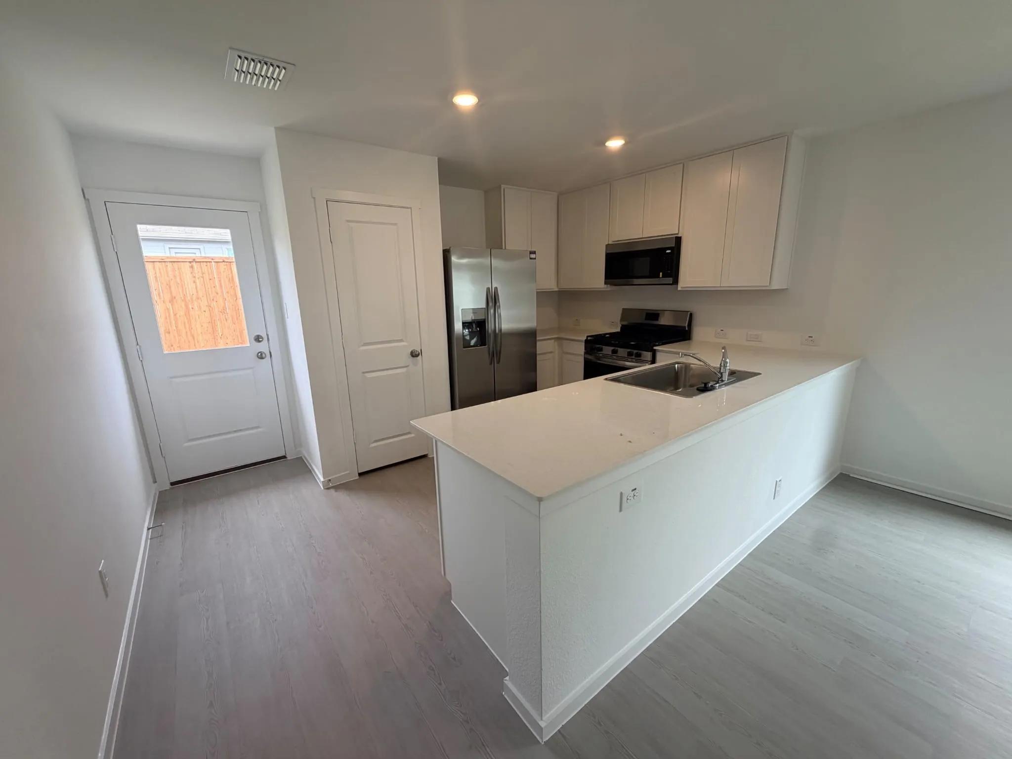 Modern kitchen featuring white cabinetry, stainless steel appliances, a gas range, and wood-finish flooring